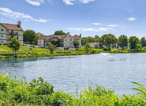 Lakefront view showcasing apartment homes, landscaped lawns, and waterfront scenery.