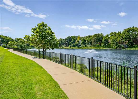 Paved walking trail along the community lake with waterfront views and green space.