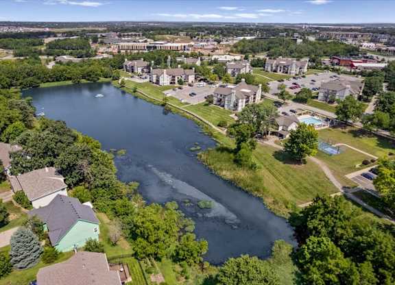 Drone view of the community lake, residential buildings, walking paths, and amenities.