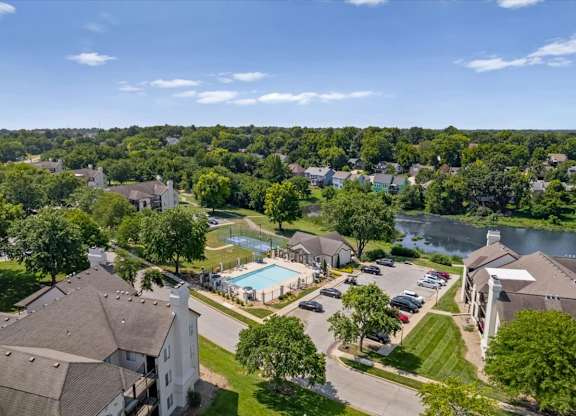 Drone view featuring the pool, basketball court, clubhouse, and surrounding apartment homes.