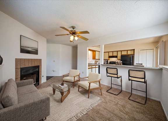 Open-concept living room featuring a fireplace, breakfast bar seating, and adjacent kitchen.