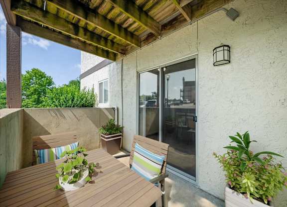 Covered patio featuring outdoor dining furniture, decorative planters, and sliding glass door access.