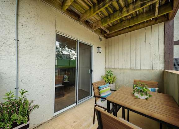 Spacious covered patio with outdoor seating, wood ceiling accents, and access to the apartment interior.