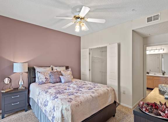 A bedroom with a ceiling fan, walk-in closet and master bathroom.