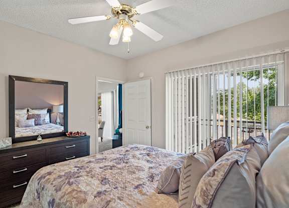 A bedroom with a ceiling fan and sliding glass patio door.