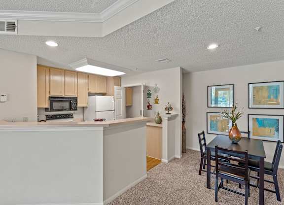 A dining area and kitchen with light wood cabinetry.