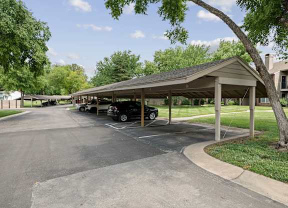 A parking lot with a covered parking area and a tree.