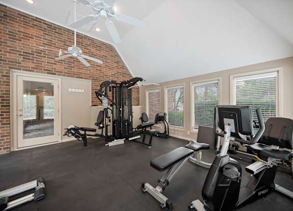 A home gym with a brick wall and a ceiling fan.