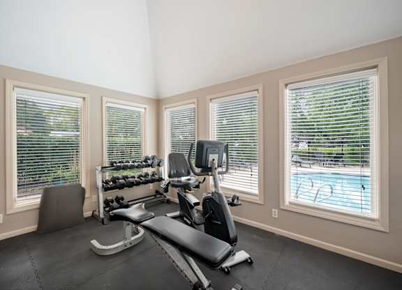 A home gym with a treadmill, weights, and exercise equipment.