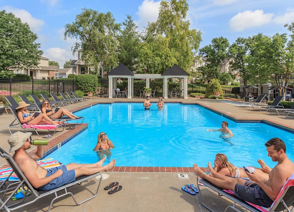 People are relaxing by the pool on a sunny day.