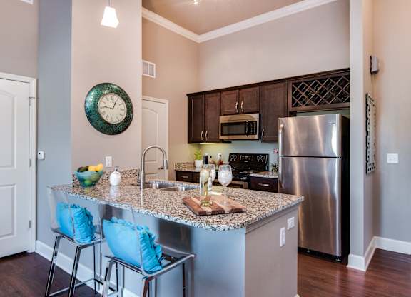 A kitchen with a granite countertop and a stainless steel refrigerator at Residences at Prairiefire Apartment Homes, Overland Park, Kansas