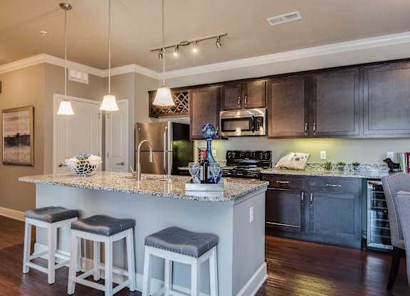 A kitchen with a bar area and stools. at Residences at Prairiefire Apartment Homes, Kansas