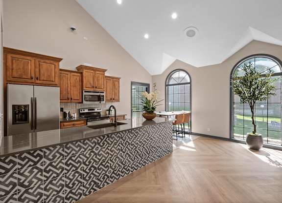 A modern kitchen with wooden cabinets and a patterned backsplash.