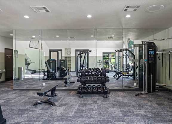 A gym with a variety of equipment including treadmills, weights, and exercise machines.