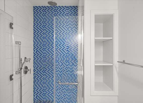 A white bathroom with a blue tiled shower.