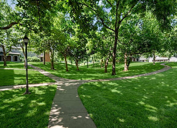 Tree-lined walking path and green space at Stonebriar Apartments in Overland Park Kansas
