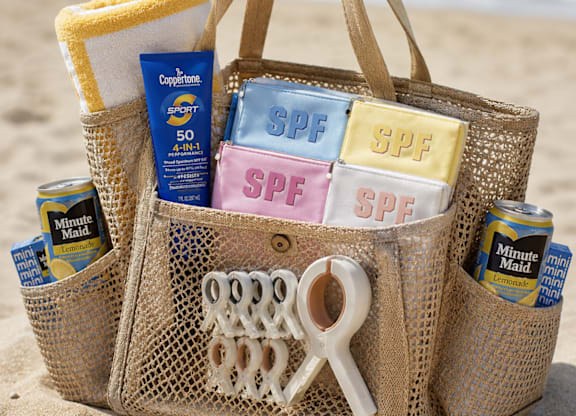 A straw bag filled with sunscreen and other beach items.