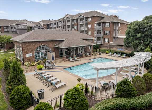 Elevated view of the outdoor swimming pool and sundeck at The Claremont Apartments, featuring lounge seating and poolside amenities.