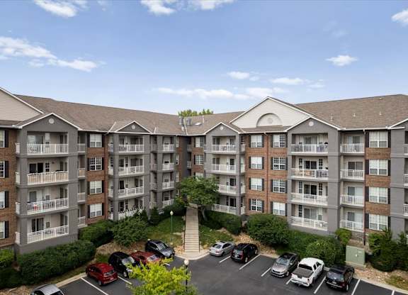 Courtyard parking area surrounded by multi-story apartment buildings with private balconies at The Claremont Apartments in Overland Park, KS.