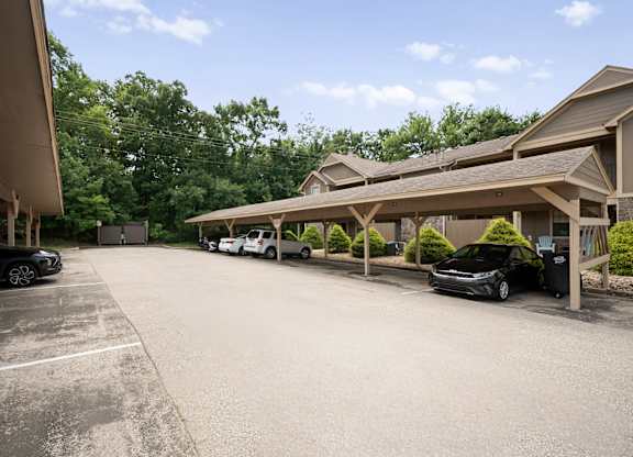 A parking lot with a building in the background and a black car parked in the lot.
