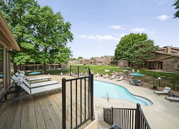 A pool area with a deck and lounge chairs.