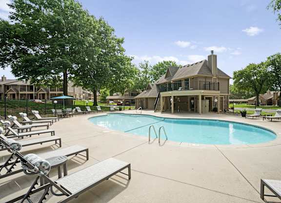 A large swimming pool surrounded by lounge chairs and trees.