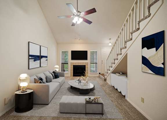 A living room with a grey couch, a fireplace, and a painting on the wall.