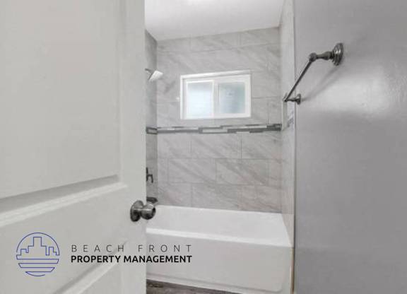 a white bathroom with a tub and a window in it
