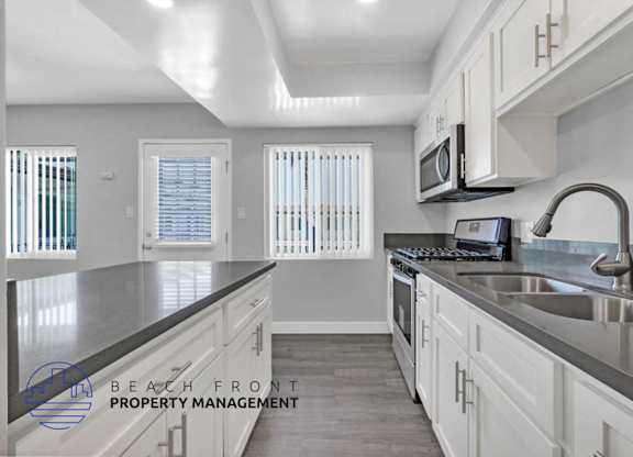 A kitchen with white cabinets and a stainless steel sink.