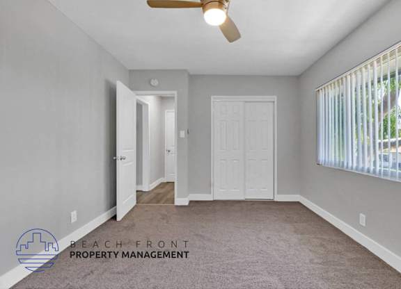 an empty living room with a white door and a window
