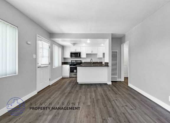 an open kitchen and living room with white walls and wood floors
