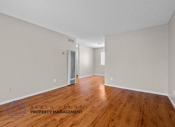 A room with wooden floors and a logo for Beach Front Property Management.