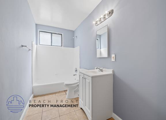 A bathroom with a toilet, sink, and mirror.