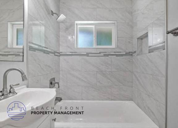 A bathroom with a marble tile wall and a white sink.