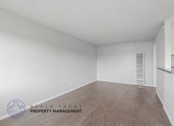 the spacious living room with wood flooring and white walls