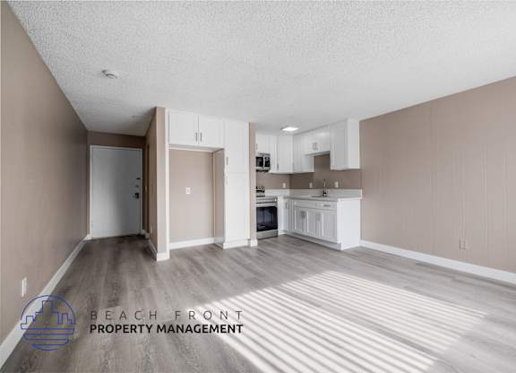 A spacious room with a kitchen area and a logo for Beach Front Property Management.