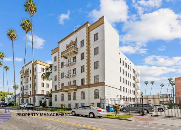 A white building with a sign that says Property Management on the bottom left.