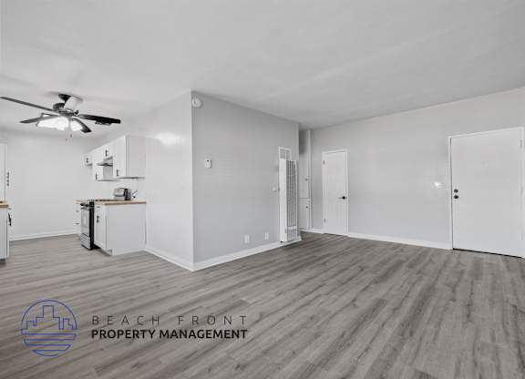A spacious room with a ceiling fan and wooden flooring.
