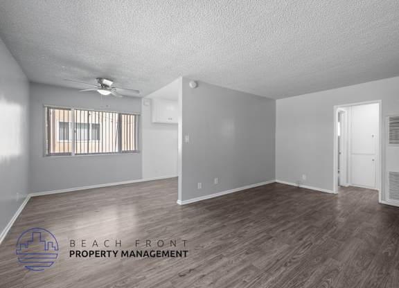 the spacious living room with hardwood flooring and a ceiling fan