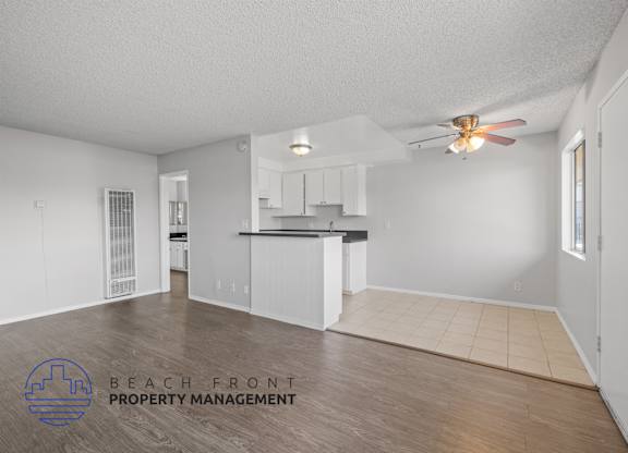 an empty living room and kitchen with a ceiling fan