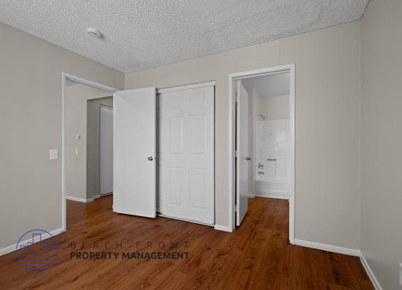 A room with a white door and a wooden floor.