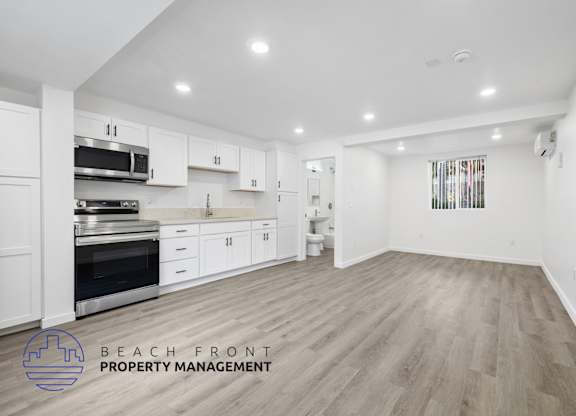 A spacious kitchen with white cabinets and a wooden floor.