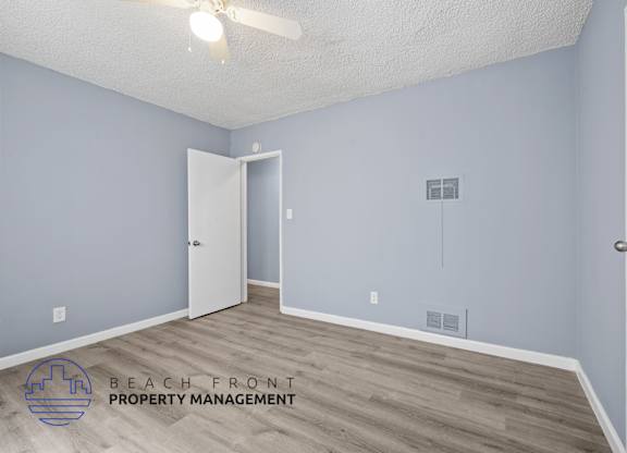 A room with a ceiling fan and a doorway leading to another room.