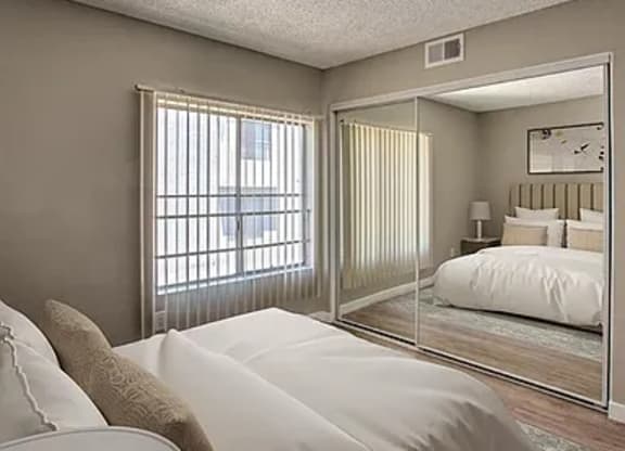 A bedroom with a large bed and a mirrored closet door.