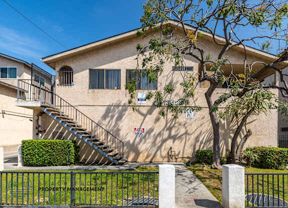 A building with a tree in front and a sign that says