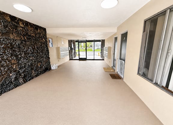 A long hallway with a stone wall on the left and windows on the right.