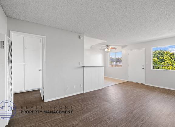 the living room and dining room of an apartment with white walls and wood floors