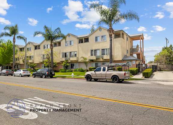 A beachfront property management logo is visible on the street in front of a row of houses.