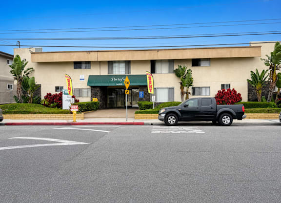 A black truck is parked in a parking space in front of a building with a green awning.