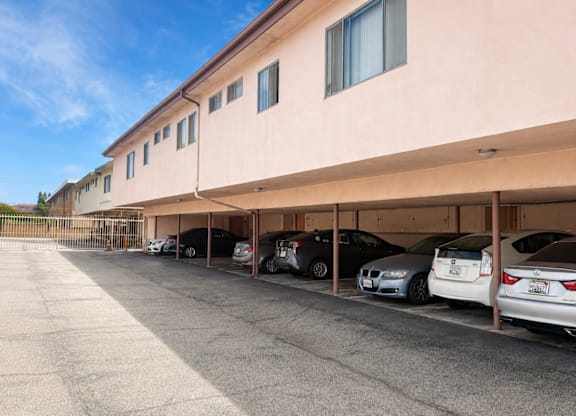 A parking lot with cars parked under a building.